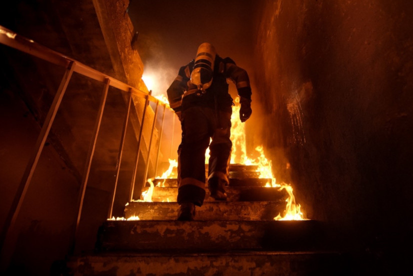 Feuerwehrmann erklimmt die Stufen eines brennenden Treppenhauses
