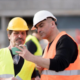 Two construction workers with one smartphone