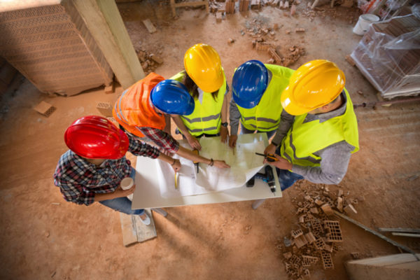Top view of construction team with colorful hard hat on building construction|Construction project coordinator and manager checking on a construction plan|A high-rise building with a dollar symbol