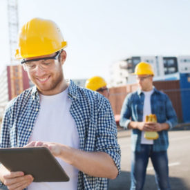 smiling site manager using tablet on construction site|smiling site manager using tablet on construction site