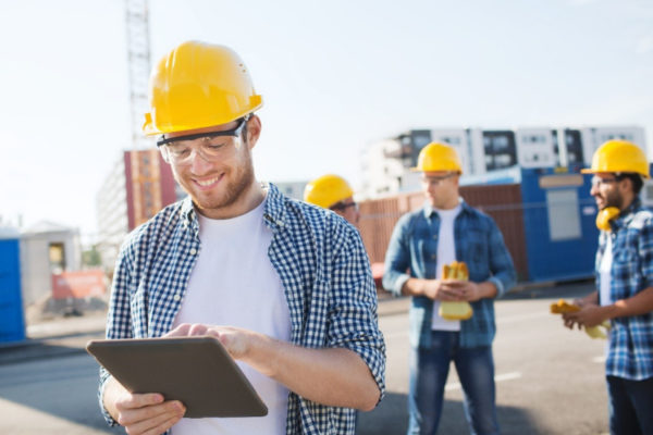 smiling site manager using tablet on construction site|smiling site manager using tablet on construction site