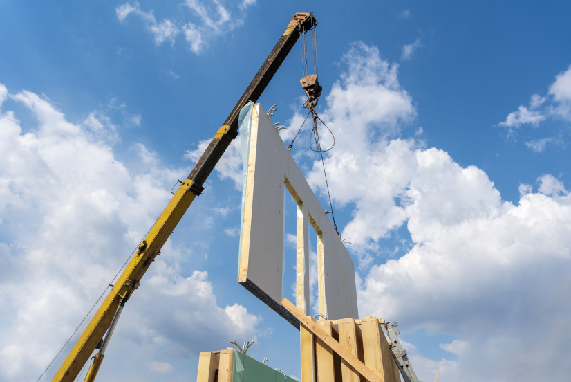 Prozess des Baues des neuen und modernen modularen Hauses von den zusammengesetzten Fertigteilwand gegen Hintergrund mit schönem blauem Himmel|Modulares bauen