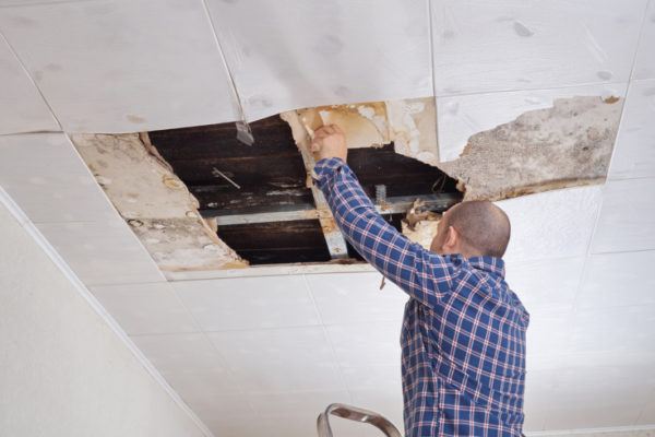 Man repairing collapsed ceiling. Ceiling panels damaged huge hole in roof from rainwater leakage.Water damaged ceiling .