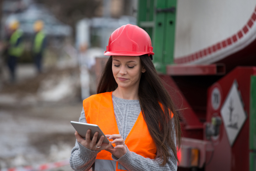 Young woman with a hardhat adding data to site diary on a tablet
