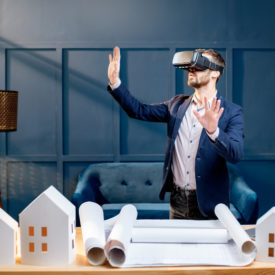 Elegant man as an architect or client imagining architectural project with virtual reality glasses standing at the working place in the luxury office