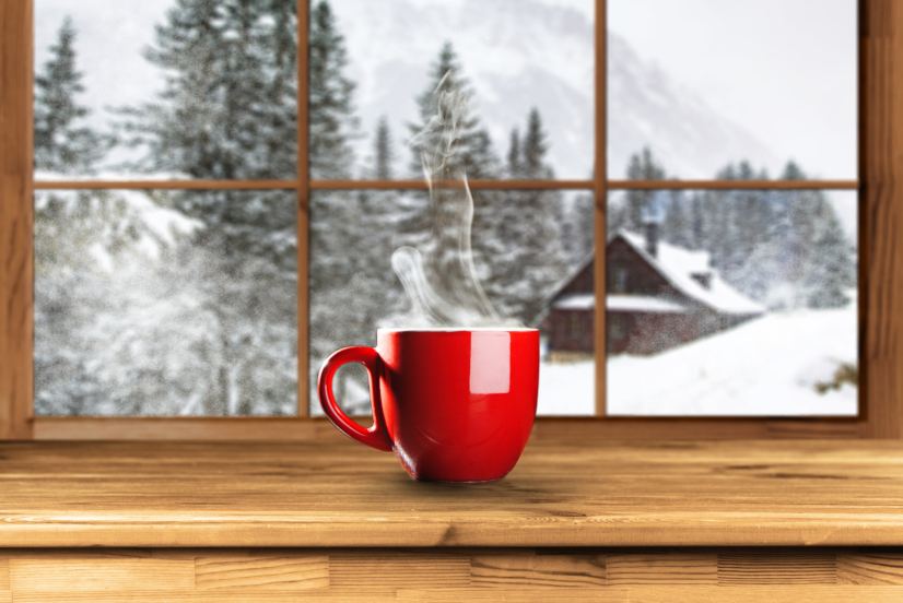 Tasse mit Kaffee oder Tee am Fenster in Winter