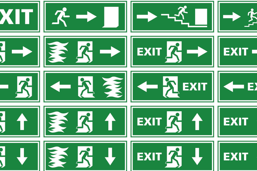 A collection of different variations of emergency exit signs / plates showing white silhouettes on green background. Various illustrations of a person or man running toward an exit door of a building to escape and find rescue, in some fleeing from a fire or flames. Some of the signs contain an arrow, stairs or the word "exit".