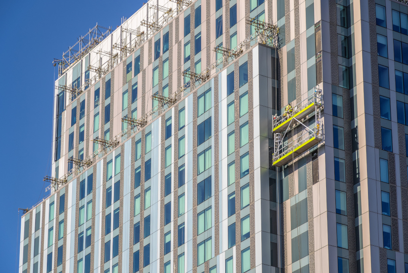 Unidentified construction workers on suspended scaffolding inspecting / installing cladding on a high rise building in London, England, UK