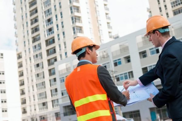 two construction professionals in construction site with checklist