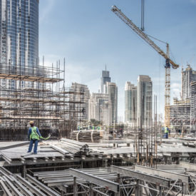 موقع بناء في دبي منطقة وسط المدينة ويظهر عمال البناء اثناء العمل وفي الخلفية برج خليفة أطول مبنى في العالم