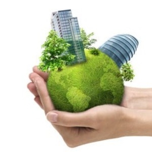 photo of a hand carrying the green earth with plants and building on it