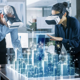 Male and Female Architects Wearing Augmented Reality Headsets Work with 3D City Model. High Tech Office Professional People Use Virtual Reality Modeling Software Application.