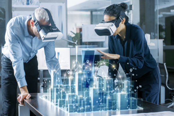 Male and Female Architects Wearing Augmented Reality Headsets Work with 3D City Model. High Tech Office Professional People Use Virtual Reality Modeling Software Application.
